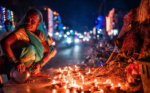 Midsection of man standing by illuminated fire at night