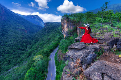 Woman sitting on rock against mountains