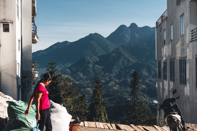 Rear view of woman with buildings against mountain range