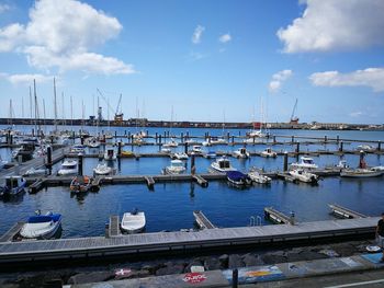 Boats moored at harbor against sky