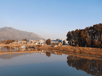 Reflection of buildings in lake against clear sky