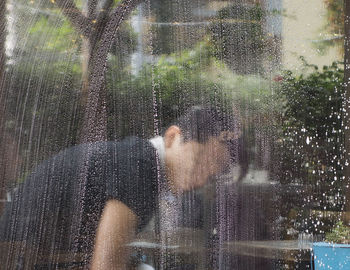 People seen through wet glass window during rainy season