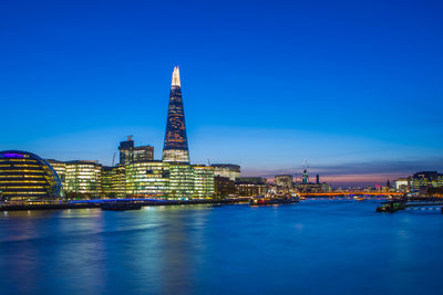 Thames river by illuminated the shard and buildings at dusk