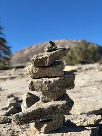 Close-up of stacked stones on mountain against clear blue sky