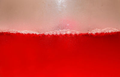 Close-up of wet glass against red background