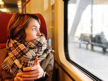 Mid adult woman looking through window while sitting in train