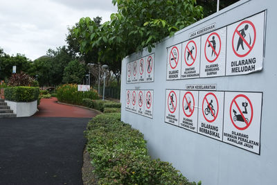 Information sign by trees in city against sky