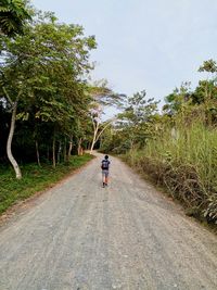 Rear view of man riding motorcycle on road against sky