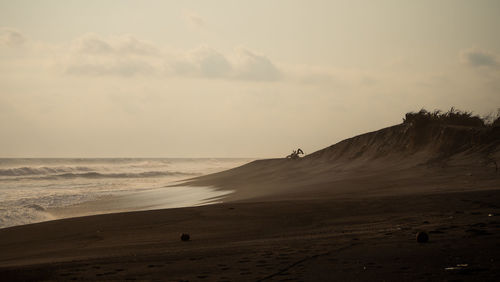 Sandy beach near ocean with big waves at sunset time in tropical resort, yogyakarta, indonesia.