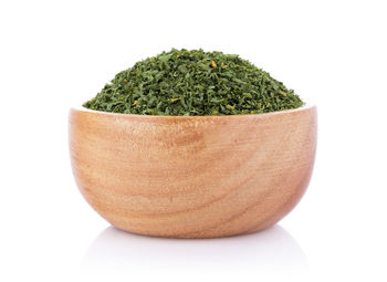 Close-up of herb in wooden bowl against white background