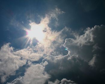 Low angle view of sunlight streaming through clouds