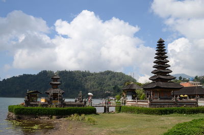 Temple building by lake against sky