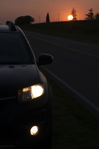 Car on street against sky at sunset