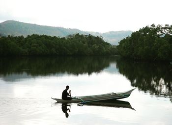 Man in boat on lake against sky