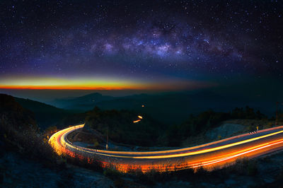 Light trails on road against sky at night