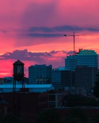 Silhouette buildings against dramatic sky during sunset