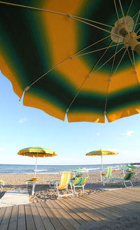 Scenic view of beach umbrellas by sea against sky
