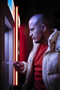 Young man using debit card at atm