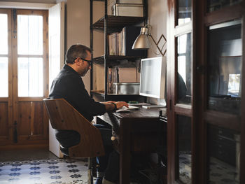 Side view of man sitting at table