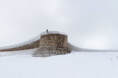 Built structure on snow covered field against sky