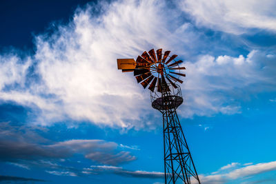 Low angle view of water pump windmill against clouds and sky