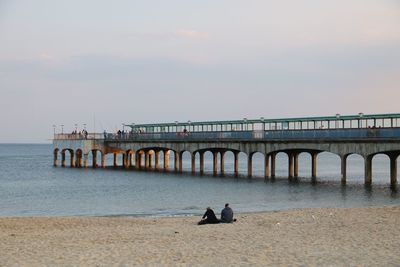 People on pier over sea against sky