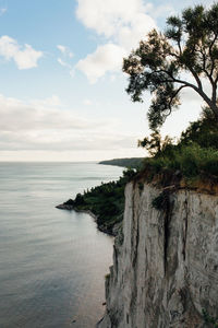 Scenic view of sea by rock formation against cloudy sky