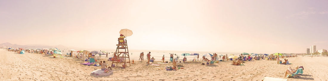 Group of people on beach against clear sky