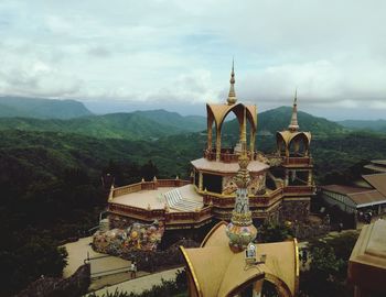 View of temple building against mountains and cloudy sky