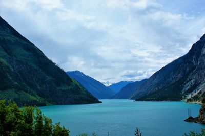 Scenic view of lake amidst mountains against cloudy sky