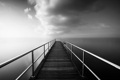 Empty pier over sea against sky