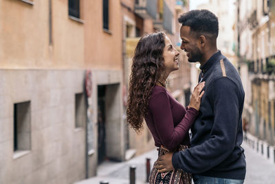 Side view of couple kissing against building