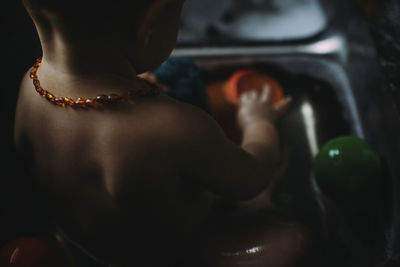 High angle close-up of baby girl playing with toys in kitchen sink at home