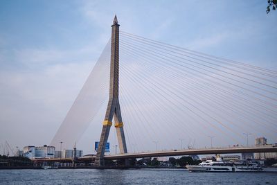 Low angle view of suspension bridge over river against sky