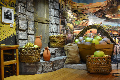 Various fruits in basket on table against wall