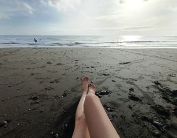 Low section of woman on beach against sky