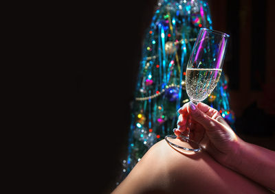 Midsection of woman holding champagne against black background