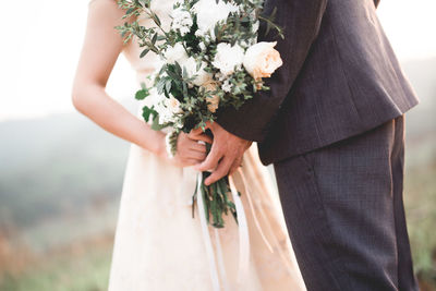 Midsection of woman holding flower bouquet