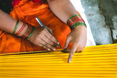 Midsection of woman marking yellow wood with marker at workshop