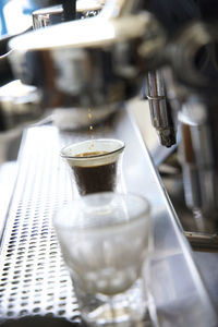 Close up of espresso maker pouring espresso into a small glass in a coffee shop