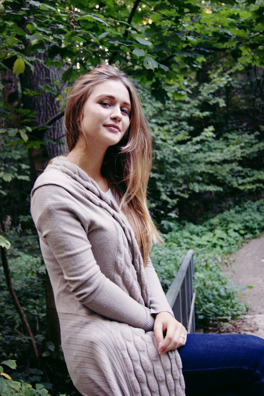 YOUNG WOMAN LOOKING AWAY WHILE STANDING ON GROUND