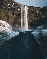 Scenic view of waterfall in forest against sky