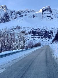 Road by snow covered mountain against sky