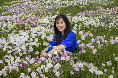 Portrait of a smiling young woman against purple flowering plants