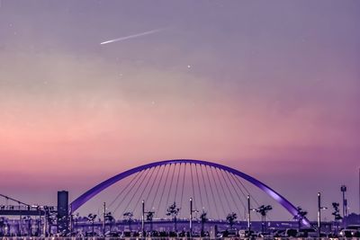 Ferris wheel in city against sky during sunset