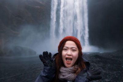 Portrait of smiling woman against waterfall