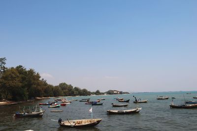 Boats moored in sea against clear sky