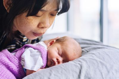 Close-up of mother by daughter sleeping on bed