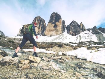 Man trekking in the alps. sharp tre cime peaks stick over the clouds in a beautiful sunny day.