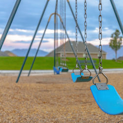 Empty swing in park against sky